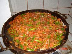 a pan filled with food on top of a stove next to a tiled wall and floor