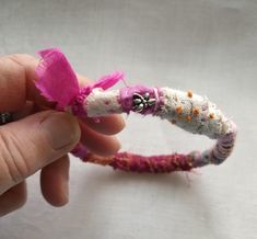 a hand holding a small pink and white piece of fabric with flowers on it's end