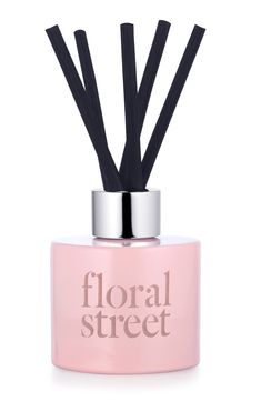 a pink bottle with black sticks sticking out of it's top that says floral street