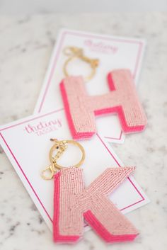 two pairs of pink and gold earrings on top of a white card next to each other