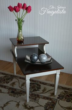 a table with two vases on top of it and flowers in the middle next to it