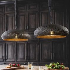 two lights hanging over a table with food on it