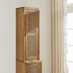 a tall wooden cabinet sitting next to a window