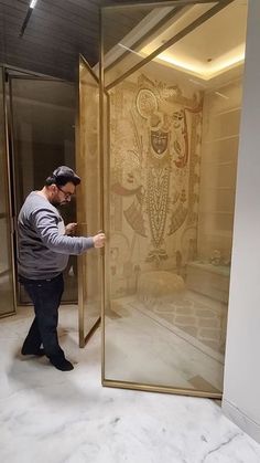 a man is standing in front of a glass door and looking at the artwork on the wall