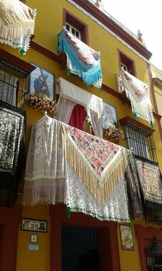 several pieces of cloth hanging from the side of a yellow building with pictures on it