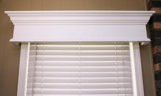 a window with white blinds and brick wall