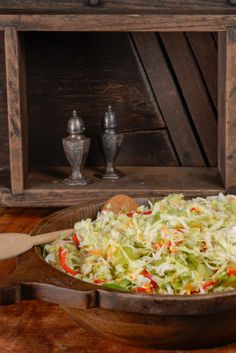 a wooden bowl filled with coleslaw on top of a table