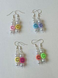 four pairs of earrings with different colored buttons and pearls hanging from the earwires