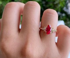 a woman's hand with a ring on it and a red stone in the middle