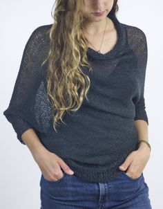 a woman with long hair wearing a black sweater and jeans is looking down at her stomach