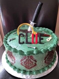 a green cake with scissors and the word clue on it