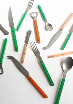 a collection of kitchen utensils and spoons on a white surface with green, orange, and grey handles