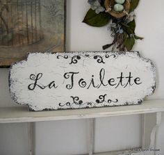 a sign that says la toilette hanging on the wall next to a shelf