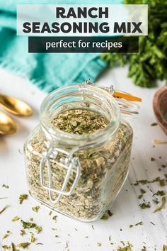 a jar filled with herbs sitting on top of a table next to gold spoons