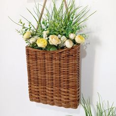 a basket hanging on the wall with flowers in it