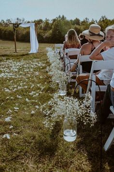 a row of white chairs sitting on top of a grass covered field