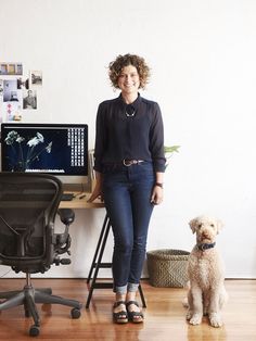 a woman standing next to a dog in front of a computer