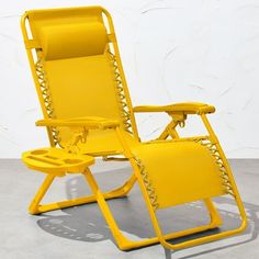 a yellow reclining chair sitting on top of a cement floor next to a white wall