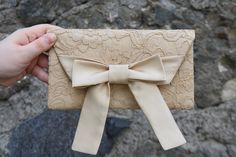 a hand holding a beige bow on top of a piece of cloth