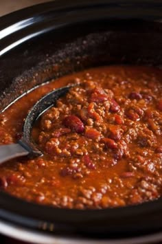 a ladle full of chili in a slow cooker