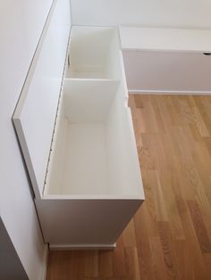 an open drawer on the side of a white cabinet in a room with hardwood floors