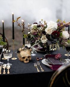 a table topped with a skull, flowers and candles