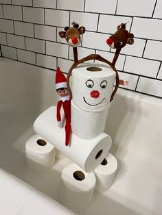 the elf is sitting on top of two rolls of toilet paper in the bathtub