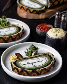 two white plates topped with food on top of a black table next to utensils