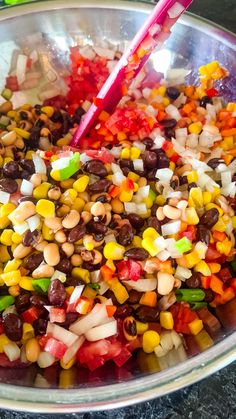 a bowl filled with lots of different types of beans and veggies next to chopsticks