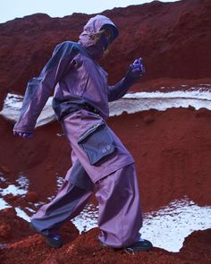 a man in purple jumpsuits standing on red dirt