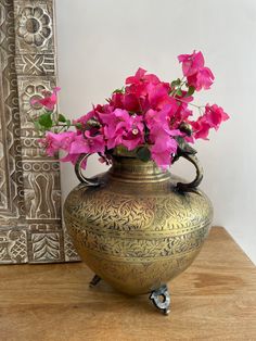 a vase with pink flowers in it sitting on a table