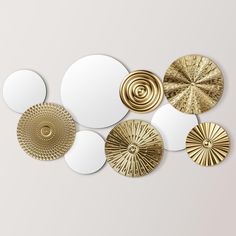 a group of mirrors with different shapes and sizes on the wall, all in gold and white