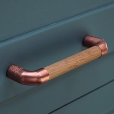 a wooden handle on the side of a blue painted dresser with wood handles and copper fittings