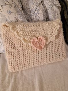 a crocheted purse with a heart on the front and inside, sitting on a bed