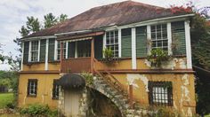 an old house with plants growing out of the windows and stairs leading up to it