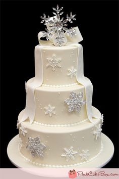 a three tiered white wedding cake with snowflakes on top