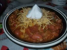 a bowl filled with chili and cheese on top of a table