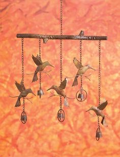 a group of birds that are hanging from a metal bar with bells on it's chains