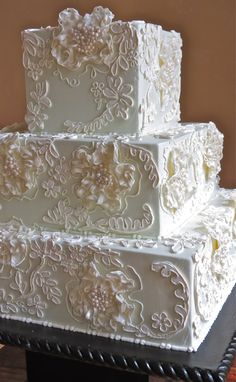 a three tiered wedding cake with white frosting and flowers on the top layer