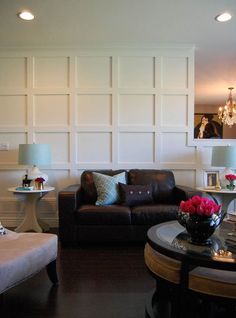 a living room with two couches and a coffee table in front of a white paneled wall