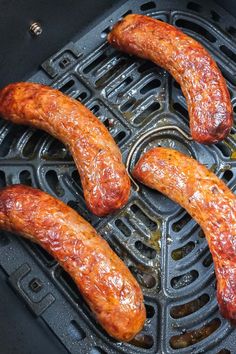 four sausages are being cooked in an air fryer