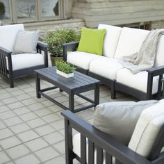 an outdoor living room with white couches and green pillows