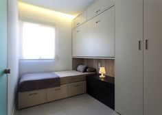 a bedroom with white cupboards and a small bed in the corner next to a window