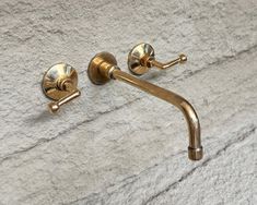 two brass faucets on the wall next to each other