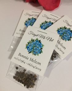 three tags with blue flowers on them sitting next to a red rose and other items