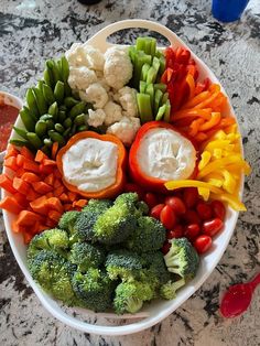 a white bowl filled with lots of different types of veggies and dips