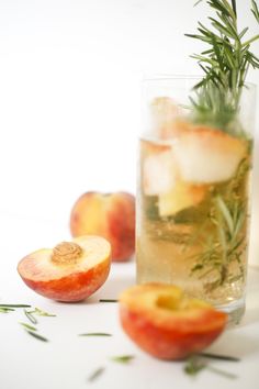 an apple and rosemary garnish in a glass with ice on the table next to sliced apples