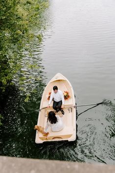 a man and woman in a small boat on the water next to each other,