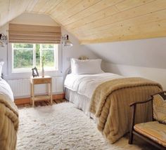 there are two beds in the attic with white blankets on them and one is made up