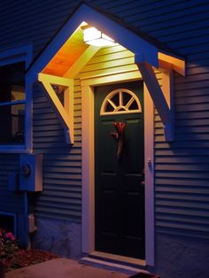 a house with a green door and white trim on the side of it at night